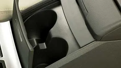 Close-up of a black car cupholder with a hinged divider in the center console.