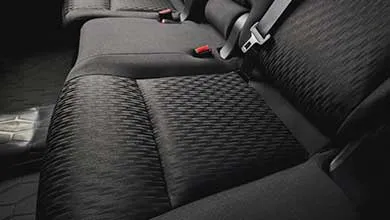 Close-up of a vehicle’s rear seats upholstered in dark gray fabric with a textured geometric pattern.